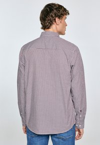 Camisa de manga larga a cuadros en rojo oscuro y blanco, material de algodón, puños abotonados y cuello clásico. Presenta un diseño de canesú.