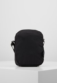 Borsa a spalla in tessuto nero con una texture liscia, forma rettangolare, tracolla regolabile e design minimalista. Nessun hardware o dettaglio visibile.