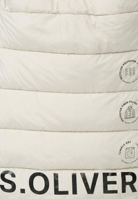 Kvitātas krēms jaka, kas izgatavota no pārstrādāta poliestera, ar lielu melnu drukātu logotipu "S.OLIVER" un apkopoto simbolu zemākajā daļā.