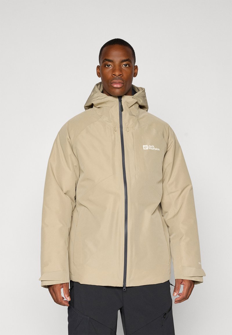 Beige waterdichte jas met een rits aan de voorkant, capuchon en logodetail. Heeft een gladde textuur en een iets losse pasvorm, ideaal voor gebruik buitenshuis.