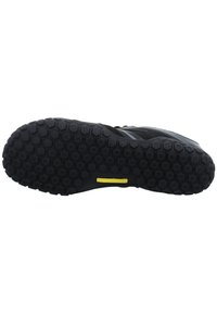 Black athletic shoe sole with a hexagonal tread pattern, featuring a yellow accent and a textured surface for traction.