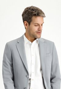 Hellgraue Sakkjacke mit strukturiertem Finish, im Einreiher-Design, mit Reverskragen und Brusttasche, getragen über einem weißen Hemd.