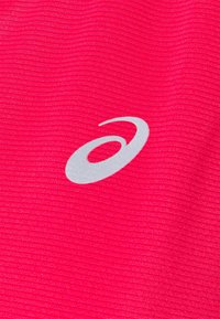 Reflecterend zilveren Asics-logo op felroze, gestructureerde stof, waarschijnlijk onderdeel van sportkleding.