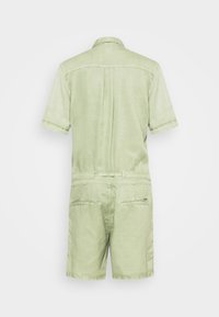 Jumpsuit corto de manga corta en verde claro con cintura ajustada, dos bolsillos traseros y una tela lisa y texturizada. Diseño sencillo con un cuello clásico.