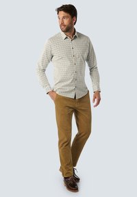 Wit overhemd met groene verticale strepen, bruine knopen; gecombineerd met beige broek en bruine schoenen. Soepele stoftextuur.