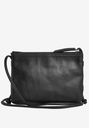 Sac bandoulière en cuir noir avec fermeture éclair et sangle fine réglable, présenté sur un fond blanc uni.