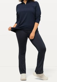 Set atletico blu navy composto da una maglietta a maniche lunghe con mezza zip e pantaloni aderenti abbinati, realizzati in tessuto leggero e liscio.