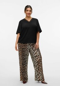 Sort V-hals top med korte ærmer parret med brede bukser med leopardmønster i nuancer af brunt og beige.