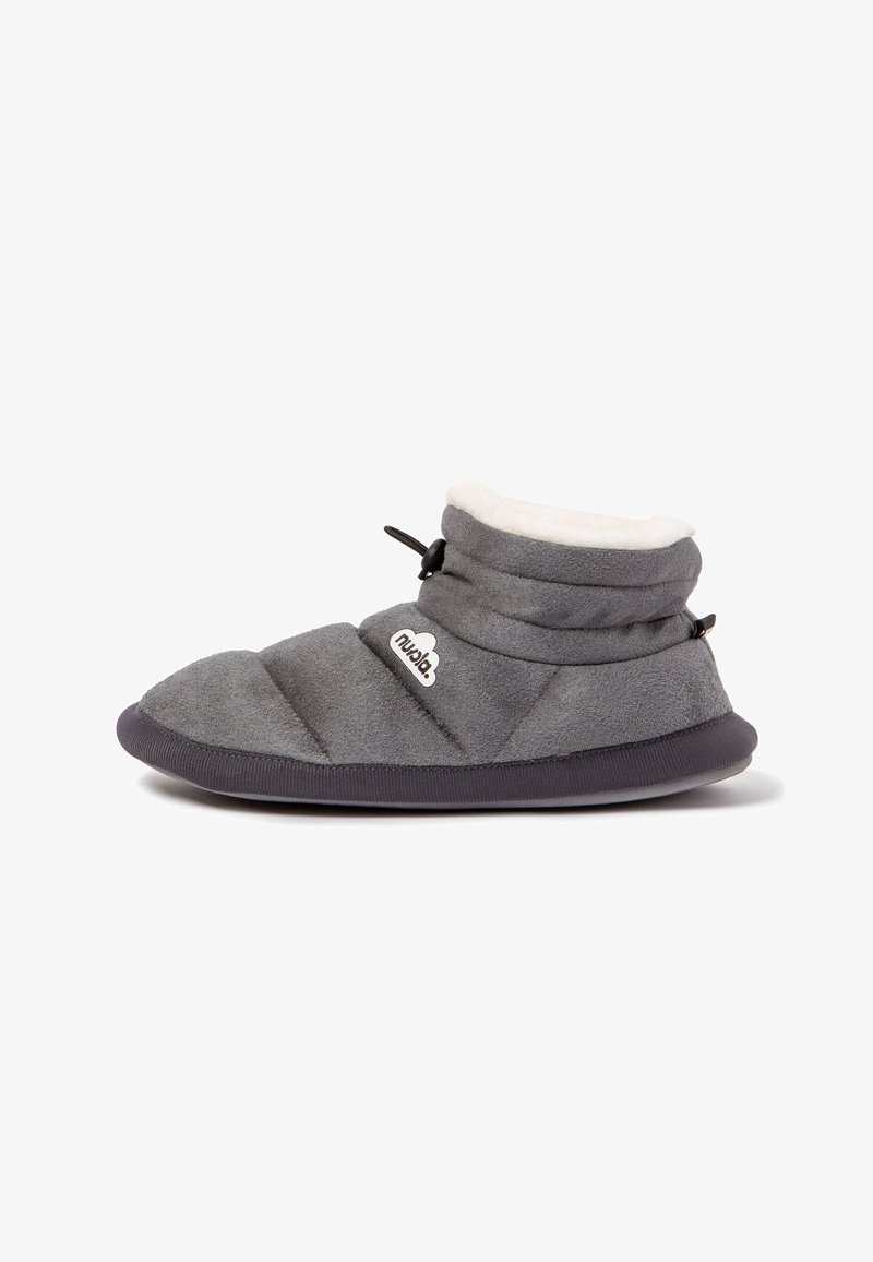 Pantufla acolchada gris con un suave cuello de forro polar blanco, acentos negros y suela de goma, que presenta un logo de marca decorativo.