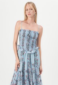 Abito floreale azzurro con corpetto smockato, orlo a volant e design a strati, caratterizzato da righe verticali e motivi floreali rosa.