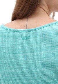 Haut côtelé bleu sarcelle clair avec un large décolleté, présentant un logo Vans discret en fil assorti à l'arrière. Texture lisse et matière douce.