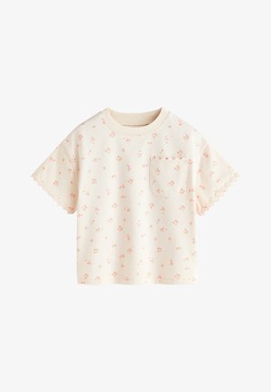 Cremefarvet kortærmet skjorte med lille pink blomsterprint, bølgede kanter på ærmerne og en matchende bølget lomme på brystet.