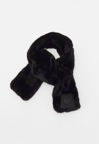 Musta tekoturkistarha, jossa on ommeltu neliön muotoinen kangas, jossa on tyylitelty sydämen kuvio, taitettuna valkoista taustaa vasten.