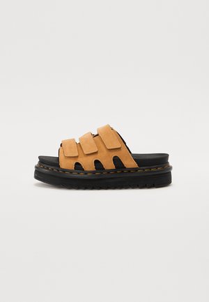 Sandale à enfiler en daim marron avec trois bandes Velcro et une semelle plateforme noire épaisse avec coutures jaunes.