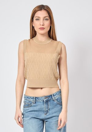 Top corto beige con un motivo testurizzato, dotato di scollo rotondo e design senza maniche, abbinato a jeans in denim.