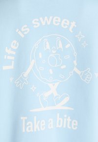 Camisa azul clara com um donut de cartoon com braços e pernas, texto branco que diz "A vida é doce" e "Dá-lhe uma mordida", com acentos de estrelas.