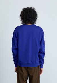 Sweatshirt blu in cotone, con collo a giro, polsini a costine e vestibilità comoda. La superficie è liscia e non presenta loghi visibili.