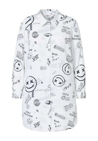 Chemise blanche à boutons avec des imprimés graphiques noirs, y compris des visages souriants et des slogans. Manches longues avec une coupe décontractée. Texture de tissu douce.