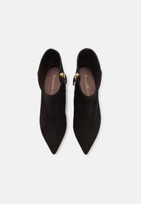 Botine negre din su; cu vârful ascuțit și accente aurii sub formă de catarame. Textură netedă, cu căptușeală moale și un design minimalist.