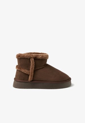Braune Stiefeletten aus weichem Wildleder mit Kunstpelzbesatz am oberen Rand und einer strukturierten Gummisohle. Einfaches Design mit minimalen Details.