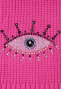 Il tessuto lavorato a maglia rosa presenta un design ad occhio decorato con pailettes e perline nere, turchesi e argentate, con accenti radianti attorno.
