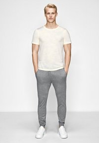 Lys gul, struktureret bomulds t-shirt med rund hals, parret med grå, tætsiddende joggers. Hvide sneakers fuldender outfittet.