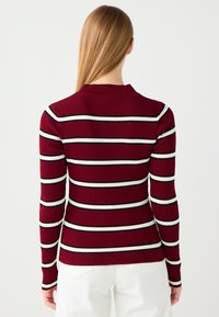Maglietta a maniche lunghe bordeaux a coste con righe orizzontali bianche e nere, dotata di scollatura rotonda e design attillato.