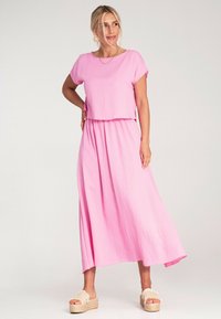 Różowy dwuczęściowy strój składający się z krótkiego topu i długiej, zwiewnej spódnicy. Wykonany z teksturowanej tkaniny, z krótkimi rękawami i elastycznym paskiem.