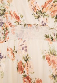 Tissu crème avec un imprimé floral orange, pêche et violet, présentant un détail de ceinture élastique froncée.