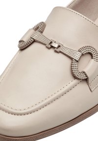 Mocassini in pelle crema con hardware argento testurizzato e design a catena. Le scarpe presentano cuciture a contrasto e una suola in gomma piatta.