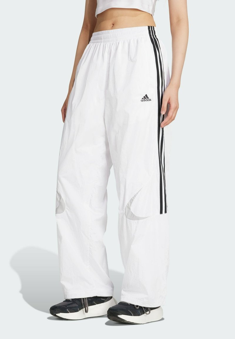 Biele teplákové nohavice s čiernymi bočnými pruhmi, vyrobené z ľahkého materiálu. Obsahujú elastický pás a reflexné akcenty na kolenách.
