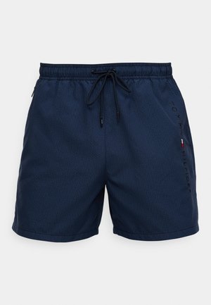 Μπλε σκούρα μαγιό σορτς με κάθετες ρίγες, ελαστική μέση, κορδόνι και πλαϊνές τσέπες. Διαθέτει το λογότυπο "Tommy Hilfiger" σε μαύρο στο μπροστινό μέρος.