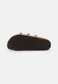 Shoe de camurça castanha com sola de borracha, apresentando um padrão texturizado, vista em ângulo que mostra o desenho de aderência da sola e os detalhes laterais.