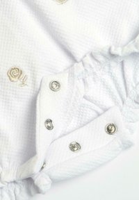 Body neonato bianco in tessuto a trama, con ricamo di rose beige e bottoni a pressione argento sul fondo per un facile cambio.