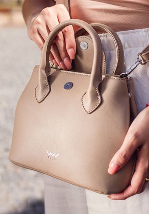 Beiger Lederhandtasche mit abgerundeten Griffen, einem metallenen Druckverschluss und einem kleinen, auf der Vorderseite eingeprägten Logo. Kompaktes Design.