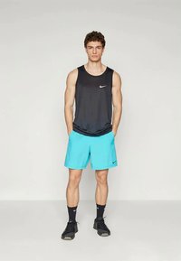 Must Nike sportlane särk mustas, koos erksinise lühikeste pükste paariga. Omadusteks on niiskust hülgav kangas ja klassikaline lõige.