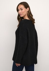 Maglione nero lavorato a maglia con vestibilità comoda, tessuto testurizzato, maniche ampie e scollatura rotonda. Sottile motivo a coste su tutta la superficie.
