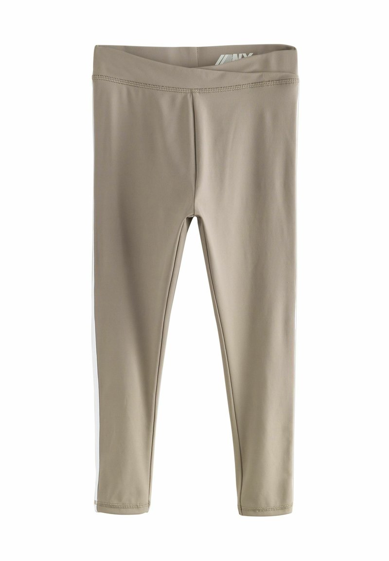 Leggings beiges en tissu extensible avec une texture lisse. Présentent une taille haute et des rayures latérales blanches contrastantes.