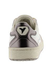 Zapatilla blanca con un tapón en el talón de color plateado metálico, suela texturizada y acento de logo negro. Textura de cuero suave y perforada.