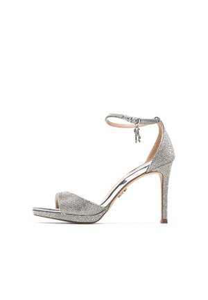 Sandalo argento con tacco alto e cinturino alla caviglia, ricoperto di piccoli strass, punta aperta e tacco a stiletto su sfondo bianco.