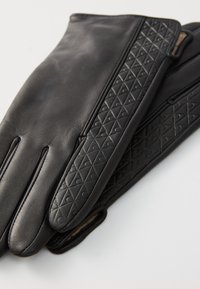 Svarte skinnhansker med en teksturert, diamantmønsterdetalj på den ene siden; glatt overflate, elegant form og åpninger for håndleddet.