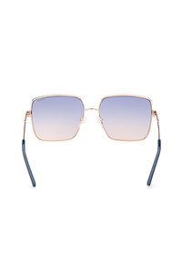 Occhiali da sole quadrati con lenti viola sfumate, montatura in metallo dorato e stanghette blu scuro. Presentano una costruzione leggera e un branding minimale.