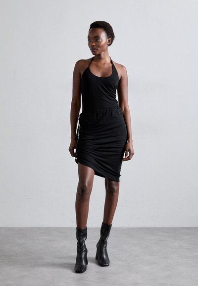 Rochie neagră cu gât halter, fabricată din material jersey, cu detalii pliate pe lateral. Asortată cu cizme negre până la gleznă, ajustate. Design simplu și elegant.