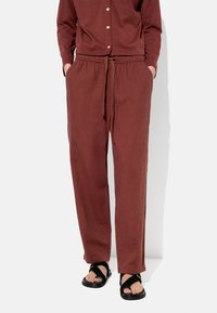 Burgundowe, luźne spodnie z elastycznym pasem, sznurkiem oraz bocznymi kieszeniami. Połączone z czarnymi sandałami o prostym fasonie z paskiem.