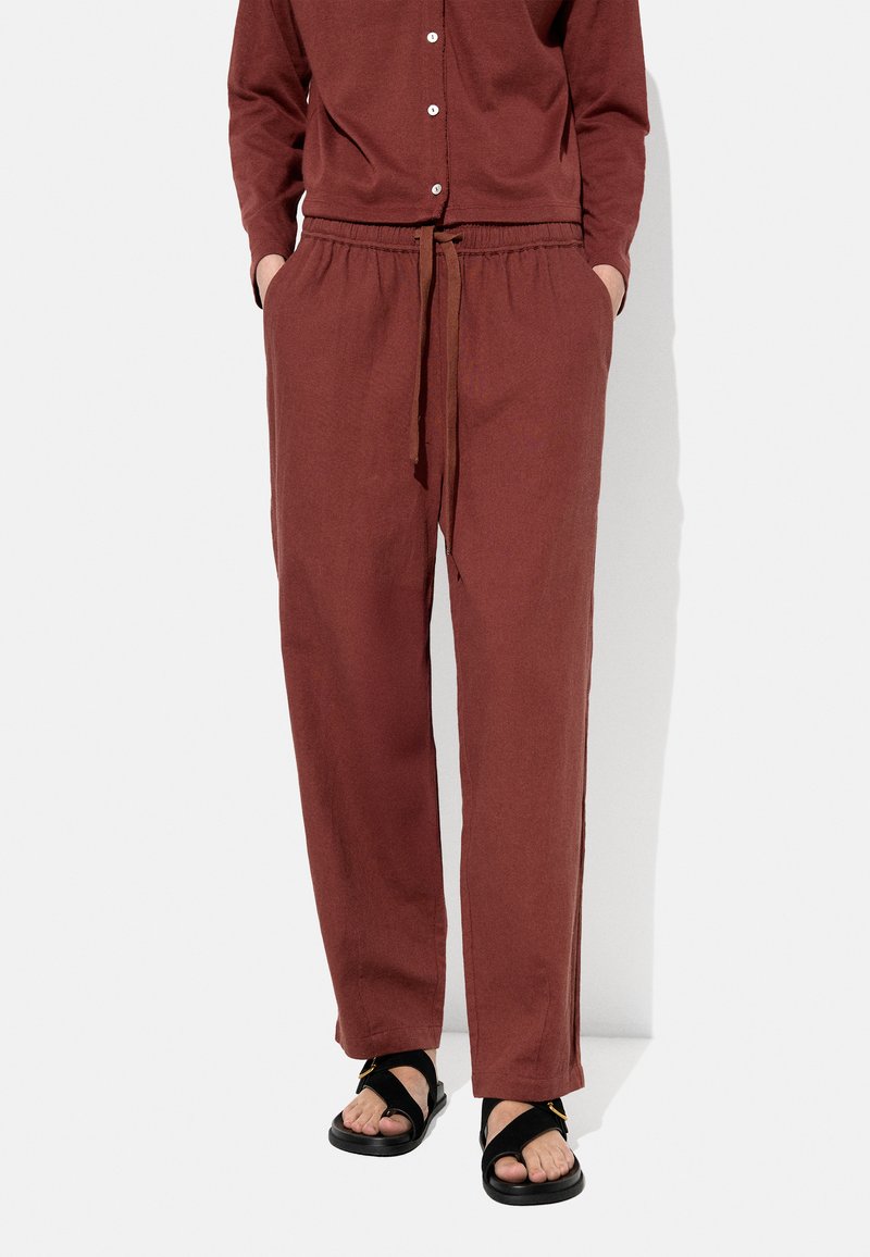 Burgundowe, luźne spodnie z elastycznym pasem, sznurkiem oraz bocznymi kieszeniami. Połączone z czarnymi sandałami o prostym fasonie z paskiem.
