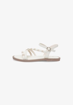 White flat sandals feature leather straps with gold-tone chain accents. The design includes an ankle strap with a buckle and a smooth sole.