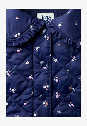 Tumed sinine tikitud jakk, millel on volangkrae, lilleline muster ja ümmargused nööbid. Sile tekstuur, kerge materjal.