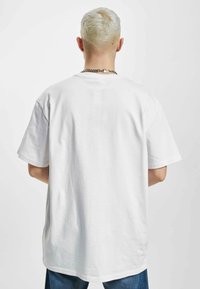 Hvid bomulds t-shirt med afslappet pasform, korte ærmer og lige kant. Bagview viser en glat tekstur og ingen synlige logoer eller mønstre.