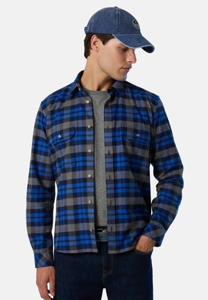 Baumwollflanellhemd mit blau-grauem Kariertmuster, zwei Brusttaschen, Knopfkragen und langen Ärmeln. Über einem grauen T-Shirt getragen.