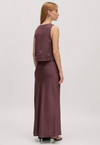 Lila twee-delige jurk met een cropped top en een lange, vloeiende rok. Zijdezachte textuur, mouwloos ontwerp, sluiting met rits aan de achterkant en een eenvoudige silhouet.
